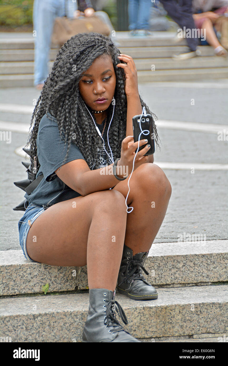 Une femme séduisante à Union Square Park à New York qui utilise son téléphone portable, lisant ou prenant un selfie. Banque D'Images