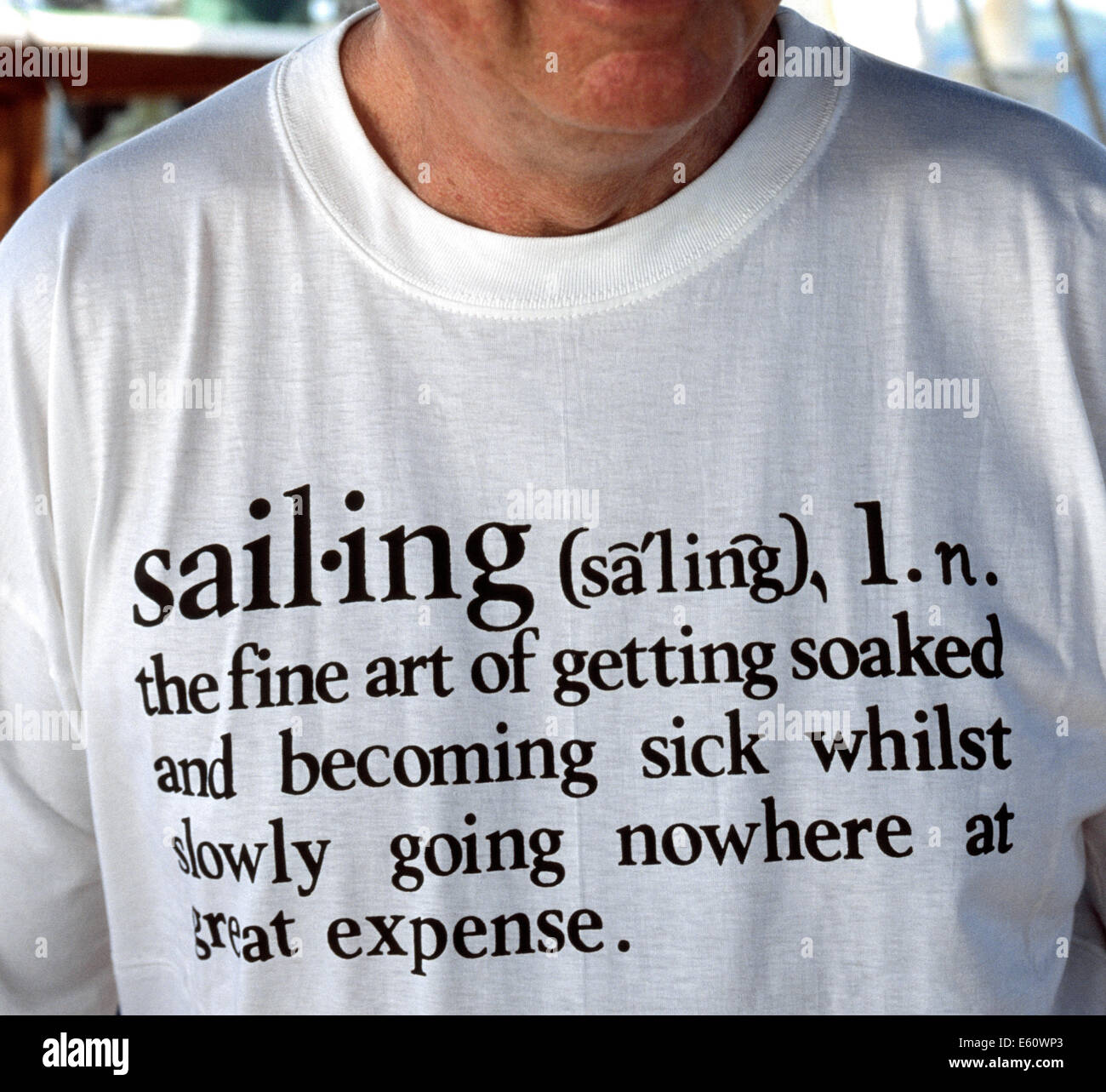 Un homme à bord d'un voilier dans la mer des Caraïbes porte un T-shirt blanc avec écrit que donne un dictionnaire humoristique-comme définition du mot "mauvaise". Banque D'Images