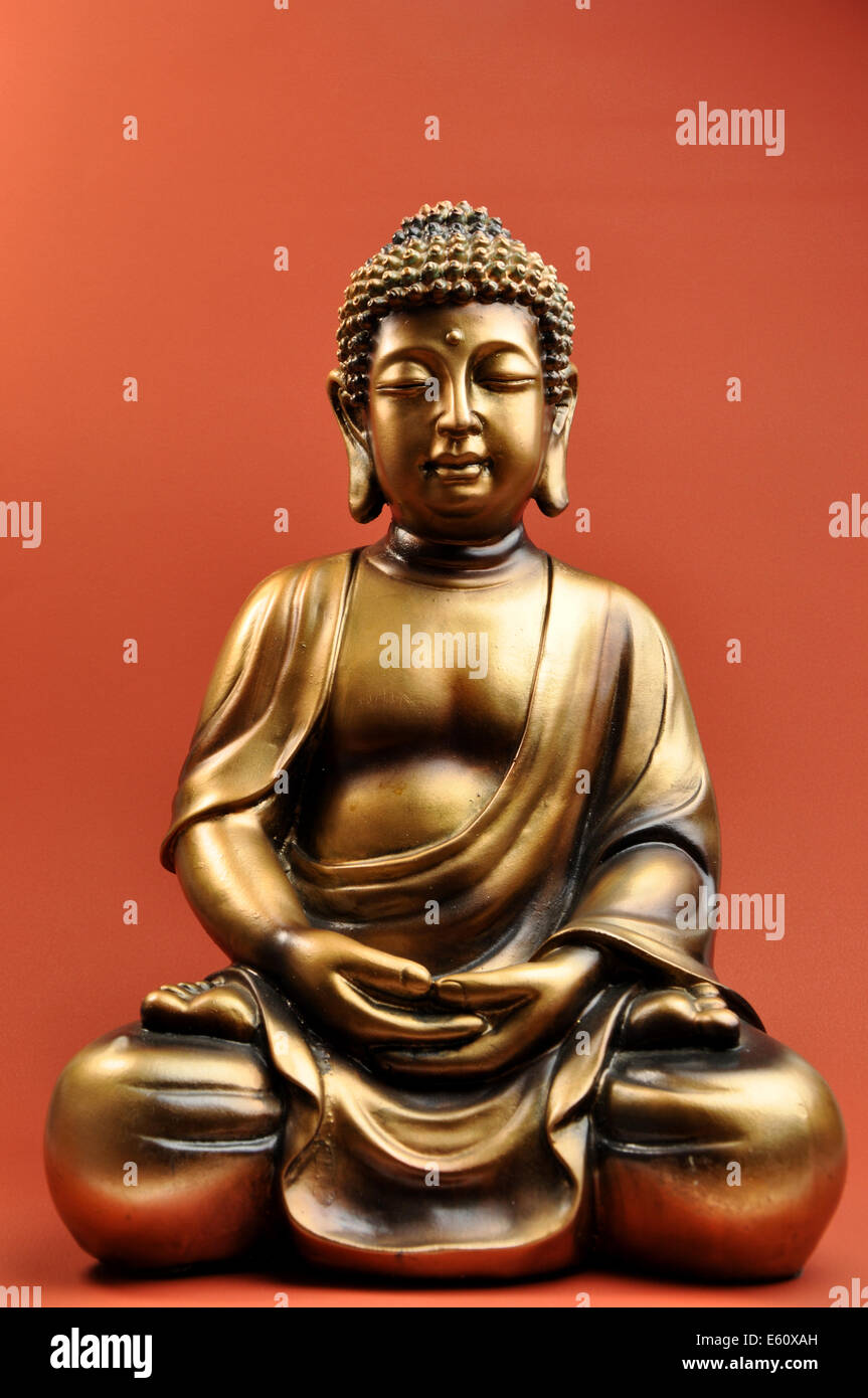 Belle statue de Bouddha avec les yeux fermés contre un fond orange rouge évoque un sentiment de paix, de calme et de tranquillité. Banque D'Images