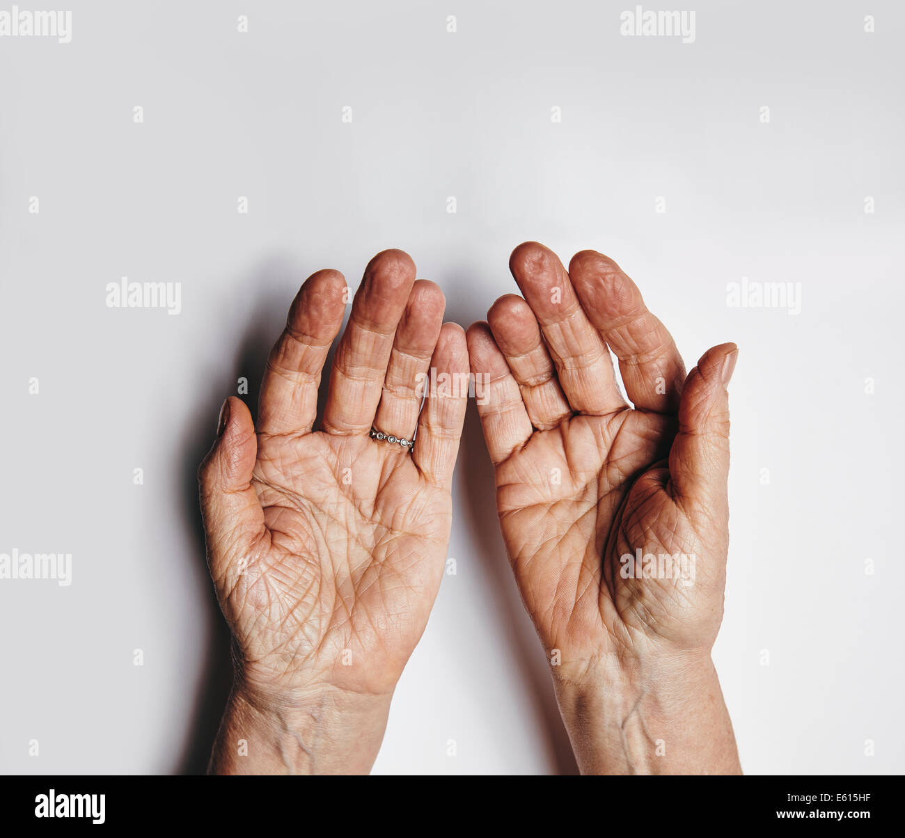 Vue de dessus de deux mains sur femelle vide fond gris. Senior woman mains suppliants. Paumes ridées de femme âgée avec spa de copie Banque D'Images