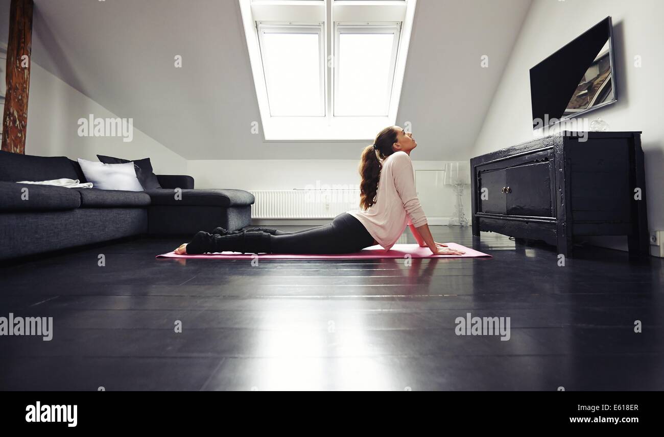 Jeune brunette woman working out exercice s'étendant sur le sol. Modèle féminin de remise en forme de l'exercice sur tapis à la maison. Banque D'Images