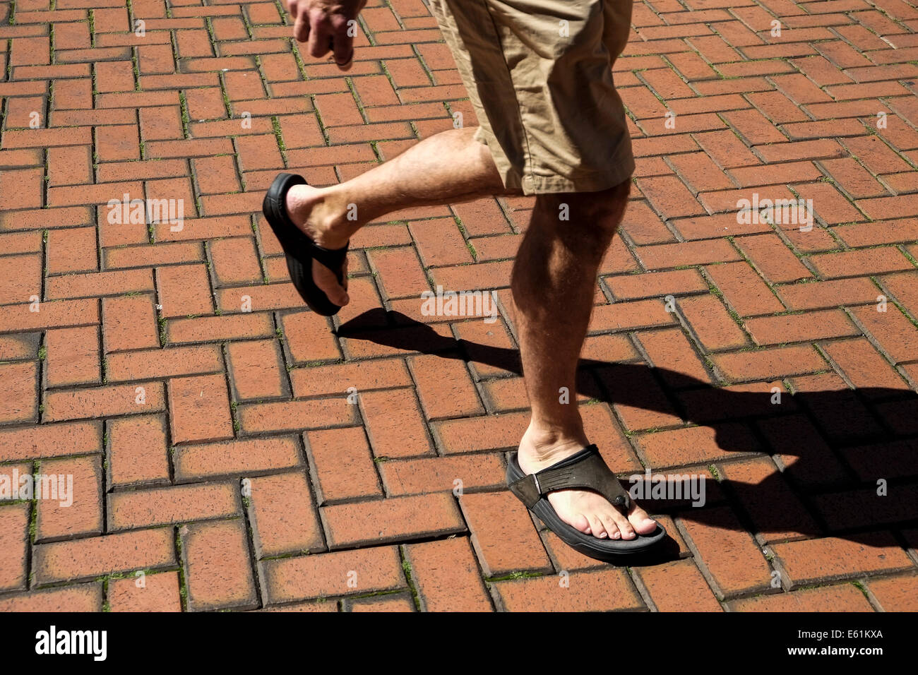 Une personne en short et sandales marcher une brique posée. étage. Banque D'Images