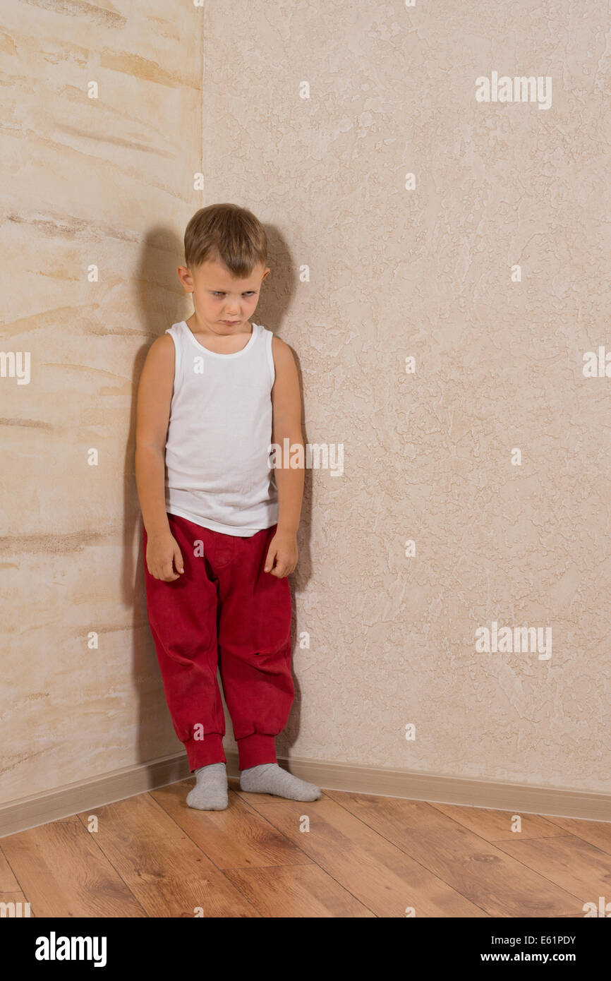 Cute Little Mad Kid portant maillot de corps blanc et rouge pantalon de jogging isolé sur des murs en bois brun clair Banque D'Images