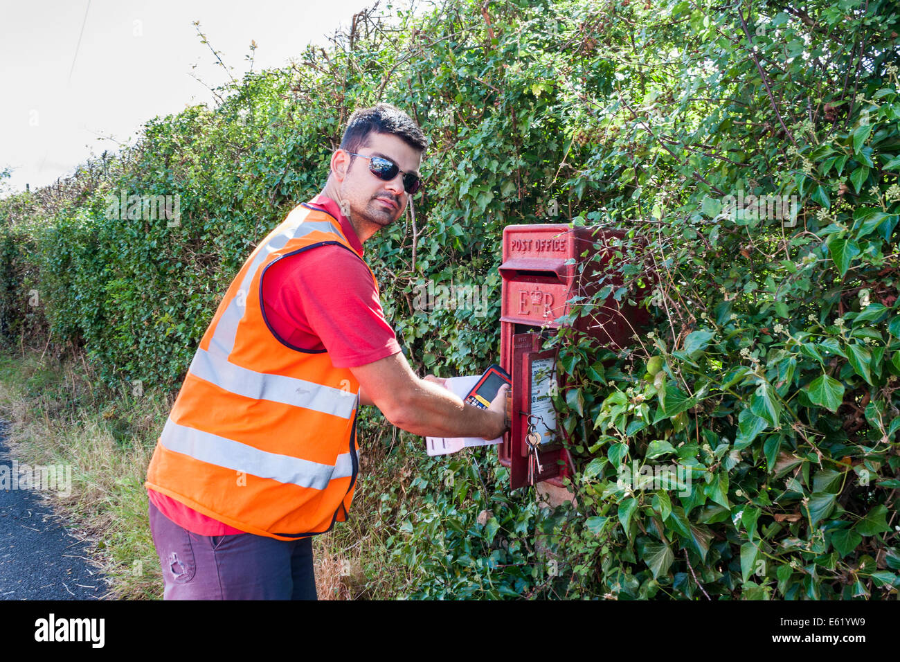 Royal Mail postman recueille des messages de pilier rural fort Banque D'Images