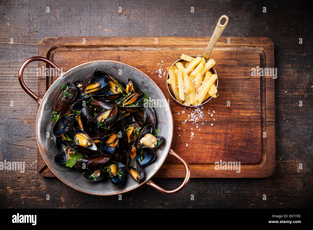 Les moules dans un plat de cuisson en cuivre et de frites sur fond de bois foncé Banque D'Images