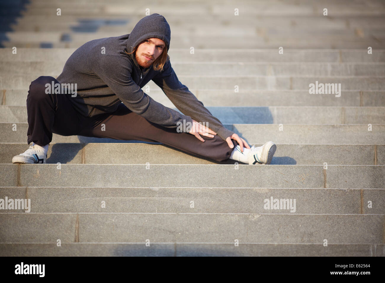 Portrait of young sportsman doing stretching de l'exercice à l'extérieur Banque D'Images