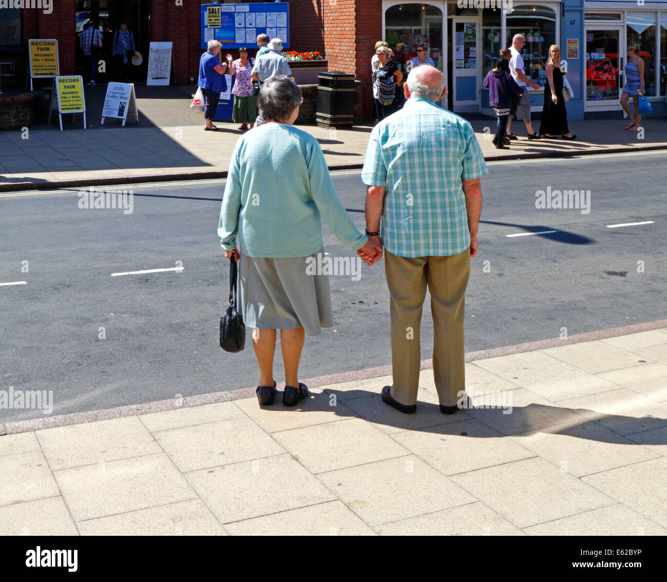 Un couple de personnes âgées se tenant la main en attendant de traverser la route à Cromer, Norfolk, Angleterre, Royaume-Uni. Banque D'Images