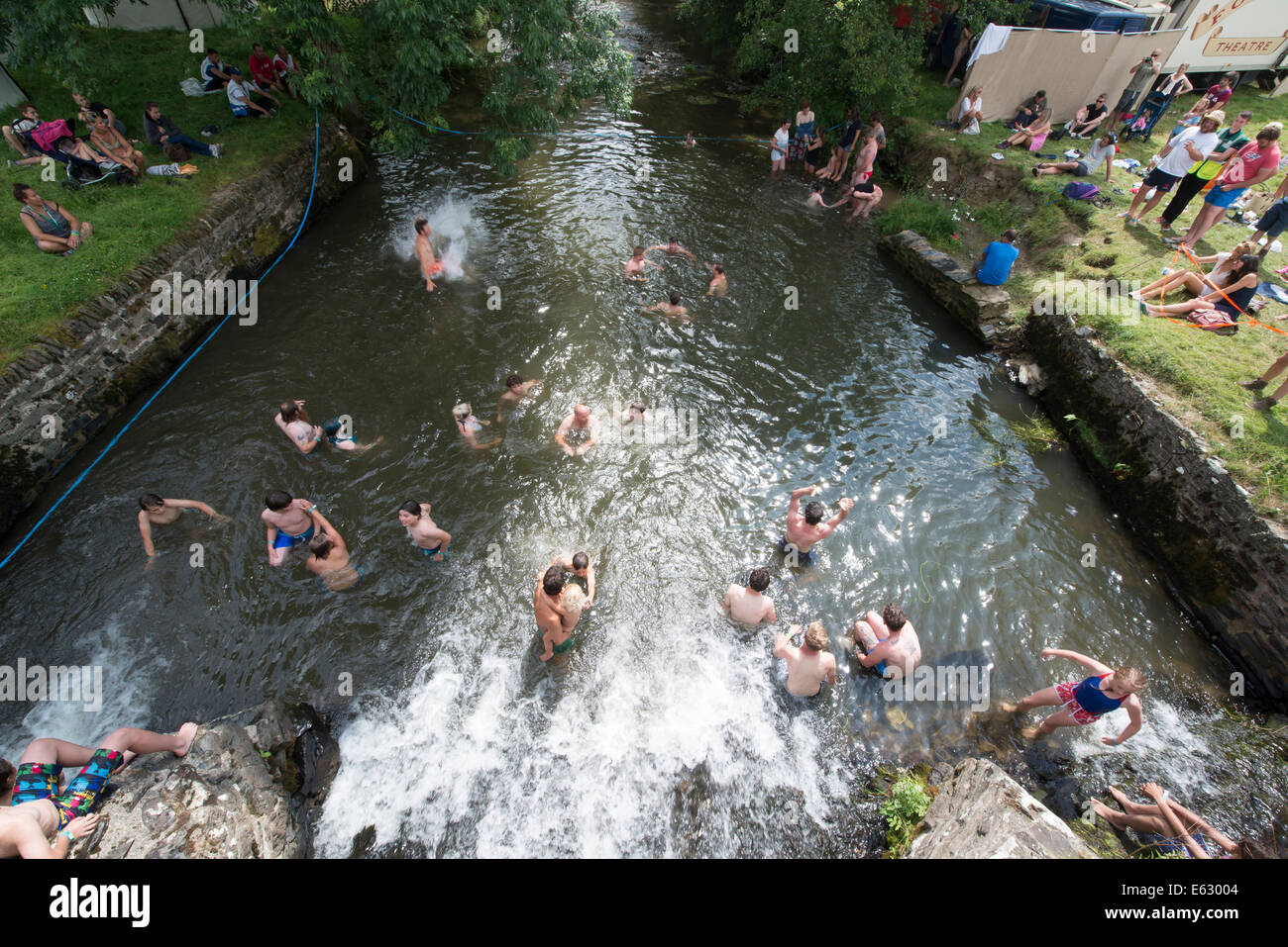 Week-end festivaliers se rafraîchir dans la rivière Bray près de Brayford au Festival somersault, Devon Banque D'Images