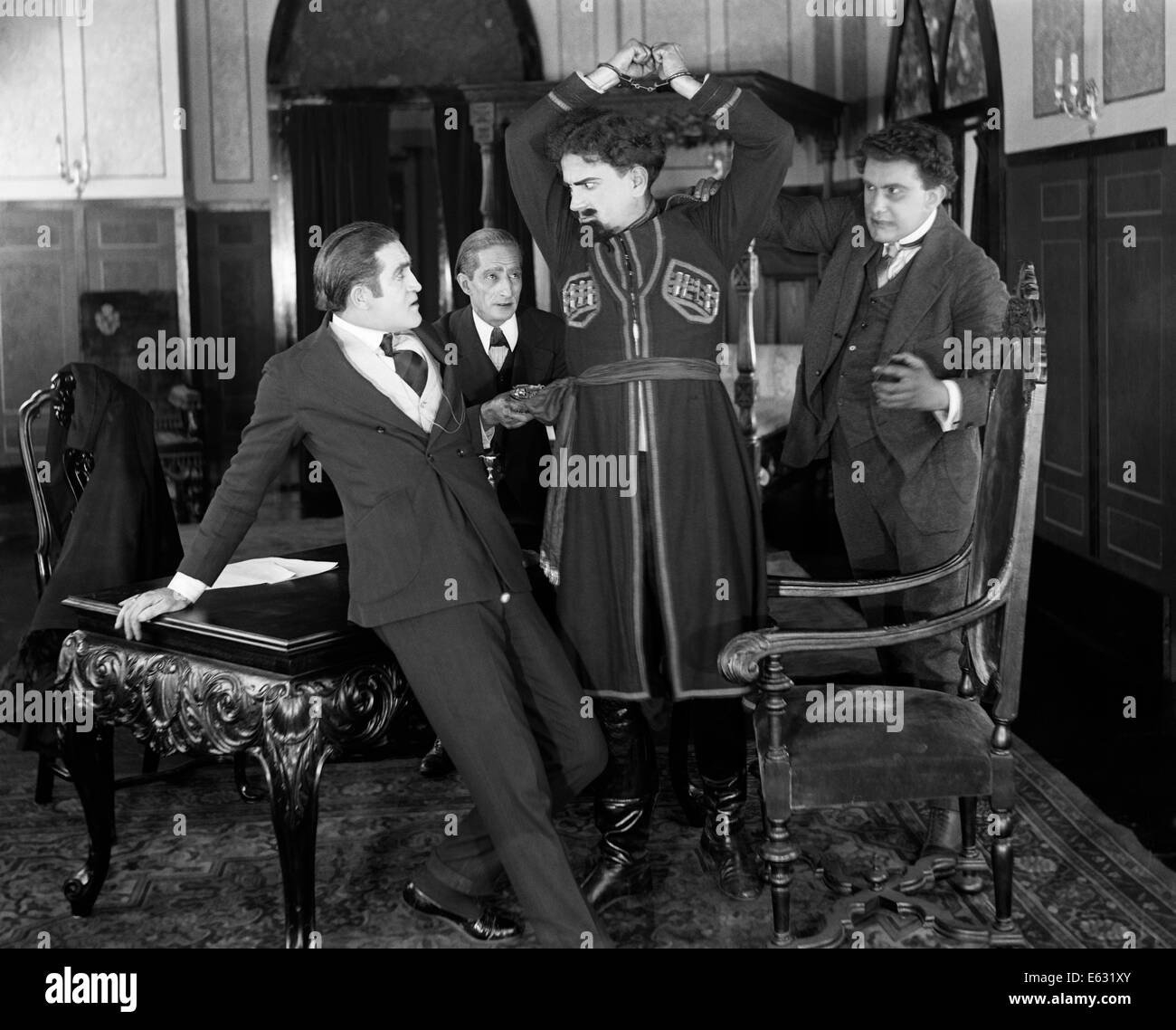 Années 1910 Années 1920 homme menotté en costume russe bras levés avec colère Banque D'Images