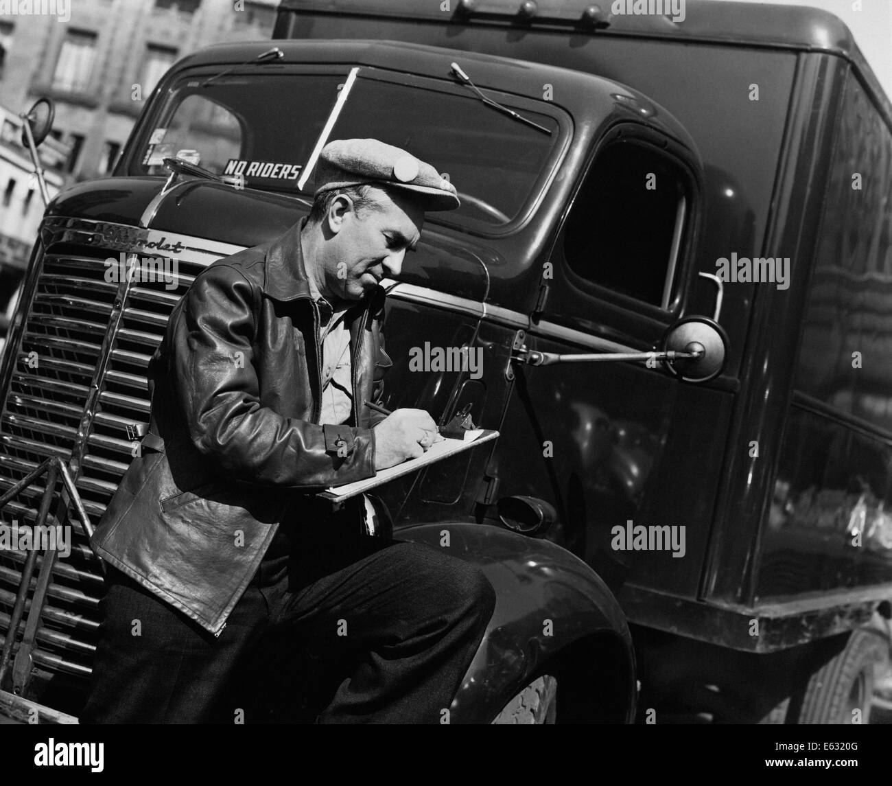 Années 1930 Années 1940 membre du syndicat de l'Homme portant chapeau en tissu AVEC BADGE et blouson de cuir par des camions de livraison de l'article WRITING ON CLIPBOARD Banque D'Images