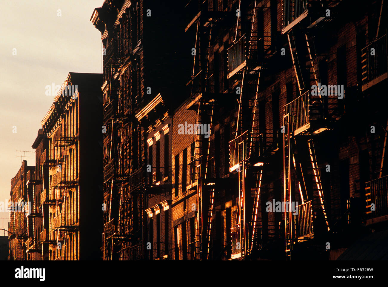 Rangée DE BÂTIMENTS RÉSIDENTIELS AVEC LE FEU S'ÉCHAPPE AU SOLEIL DE L'APRÈS-MIDI LA VILLE DE NEW YORK Banque D'Images