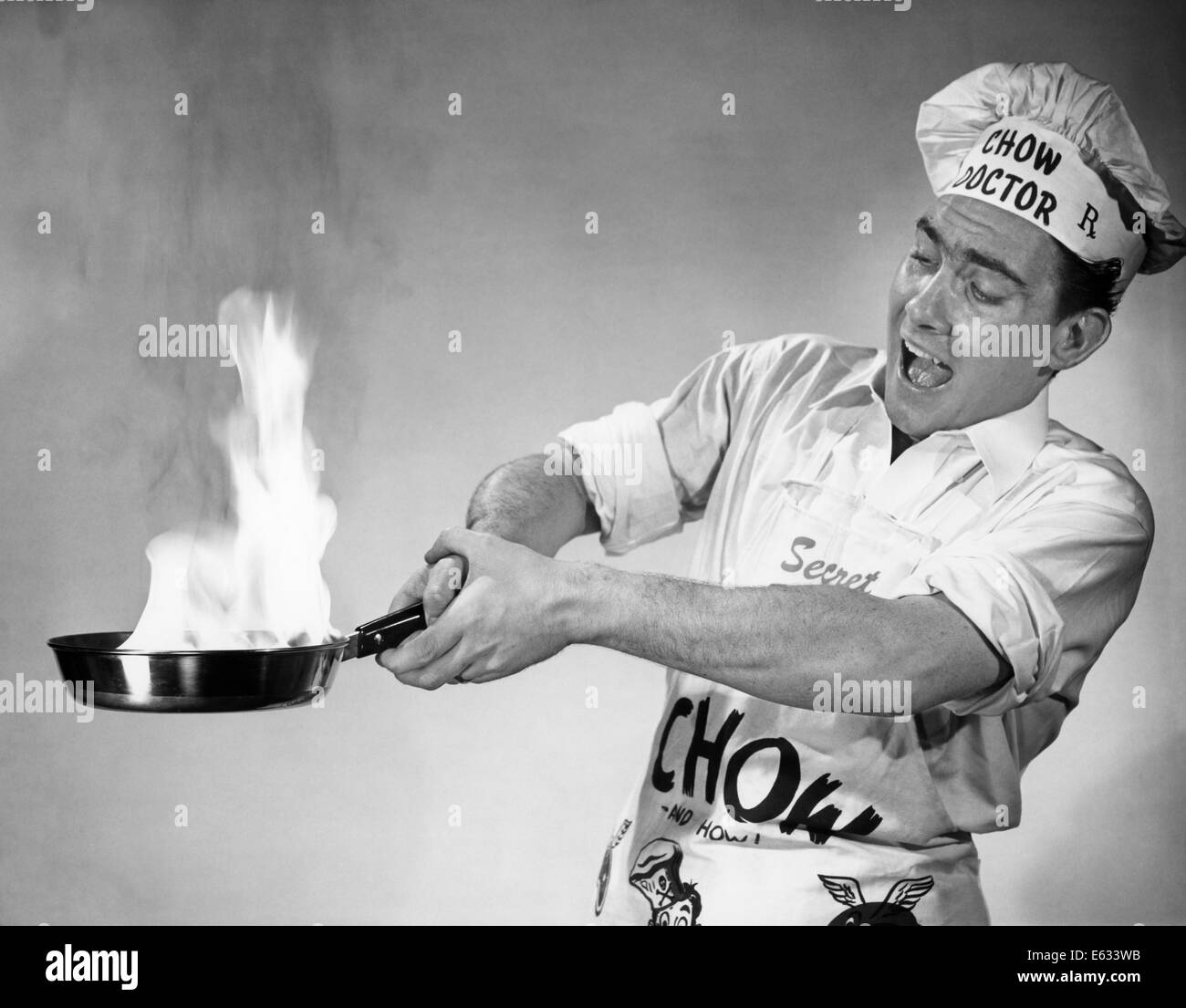 1950 FRANTIC MAN FLAMING POÊLE À FRIRE D'INCENDIE SUR LE PORT DE TABLIER ET CHAPEAU DE CHEF Banque D'Images