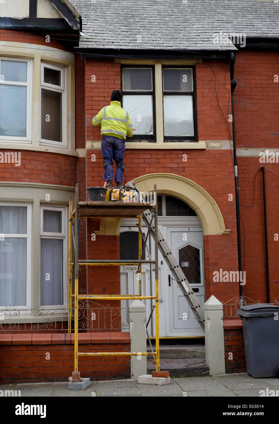 L'homme sur la maçonnerie rejointoiement tour d'échafaudage sur la façade d'une maison mitoyenne Banque D'Images