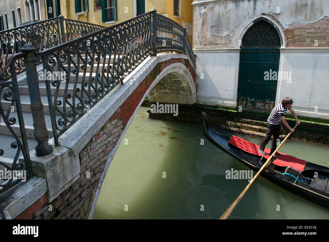 Venise, Italie - CIRCA AVRIL 2013 : Gondolier gondola pousse sous pont décoratif sur petit canal. Banque D'Images