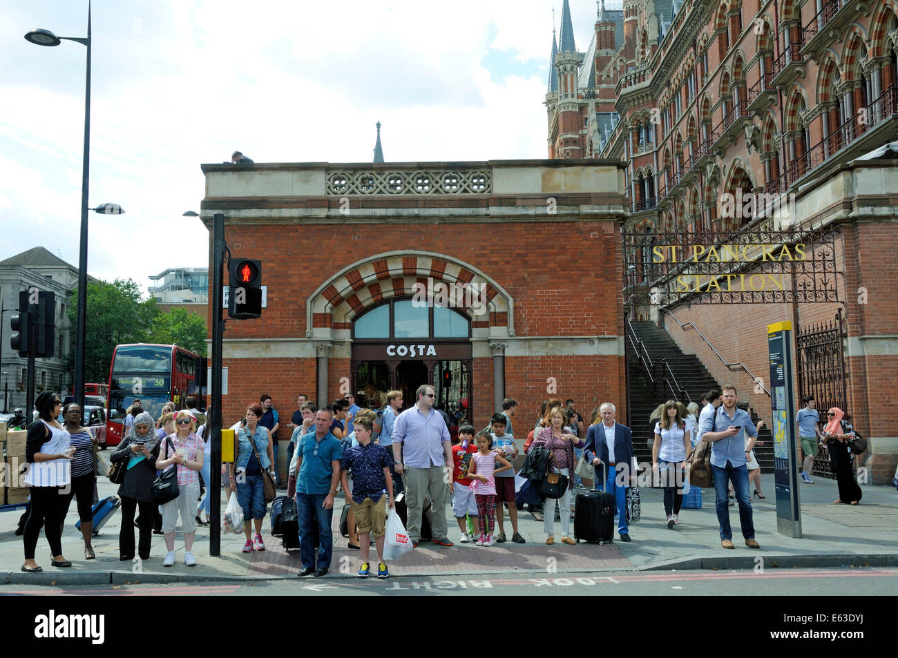 Les piétons en attente de cross road, Kings Cross St Pancras avec derrière, le centre de Londres Angleterre Royaume-uni Grande-Bretagne Banque D'Images