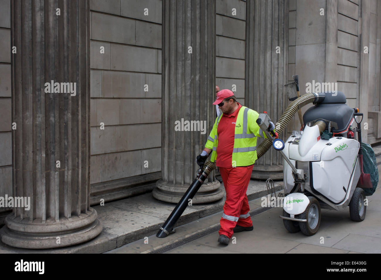 Une société de London street cleaner avec protection magnétothermique Amey plc, hoovers sous litière piliers de la Banque d'Angleterre. Banque D'Images