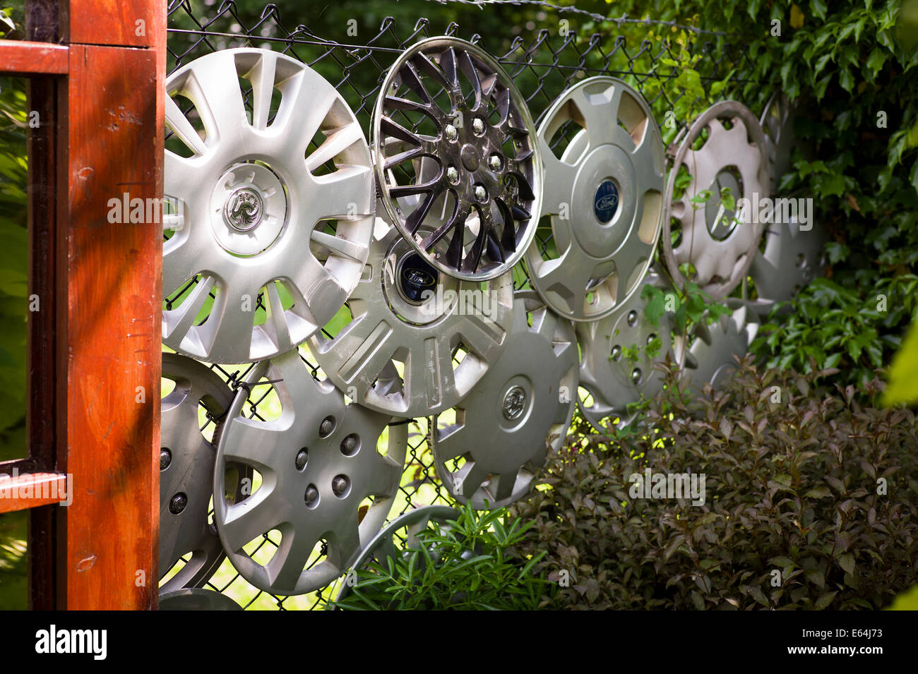 Les moyeux de roue de voiture trouvé utilisé pour décorer une clôture métallique dans un petit jardin Banque D'Images