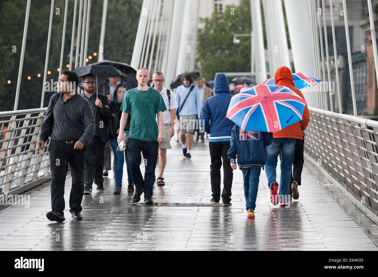 Golden Jubilee Bridge, Londres, Royaume-Uni. 14 août 2014. Les précipitations a frappé Londres aujourd'hui que le Met Office a émis des avertissements de temps violent et l'Agence de l'environnement mettre 19 alertes inondations dans tout le pays, dont 8 dans le sud-est. Sur la photo : les navetteurs et les touristes à pied à travers le Golden Jubilee Bridge à Londres comme la capitale est touchée par de fortes pluies. Credit : Lee Thomas/Alamy Live News Banque D'Images