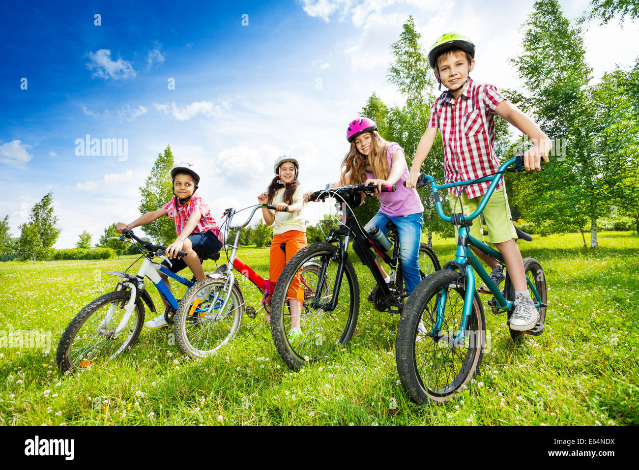 Enfants heureux dans des casques de vélo Vélos holding Banque D'Images