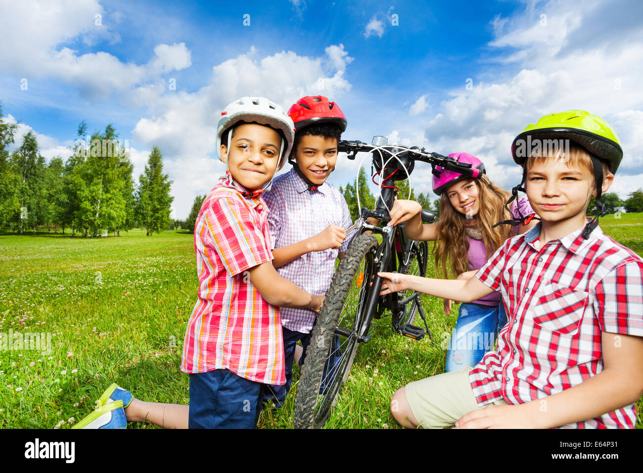 Heureux les enfants en vélo réparation casques colorés Banque D'Images