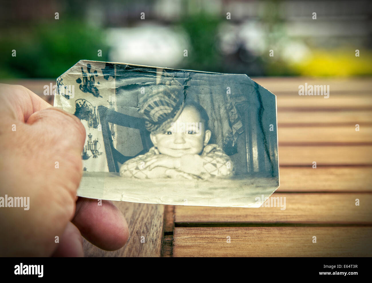 L'homme est titulaire d'une photo d'enfance des années 60 dans sa main. Strong vignettage et bords flous pour augmenter l'effet de mémoire Banque D'Images