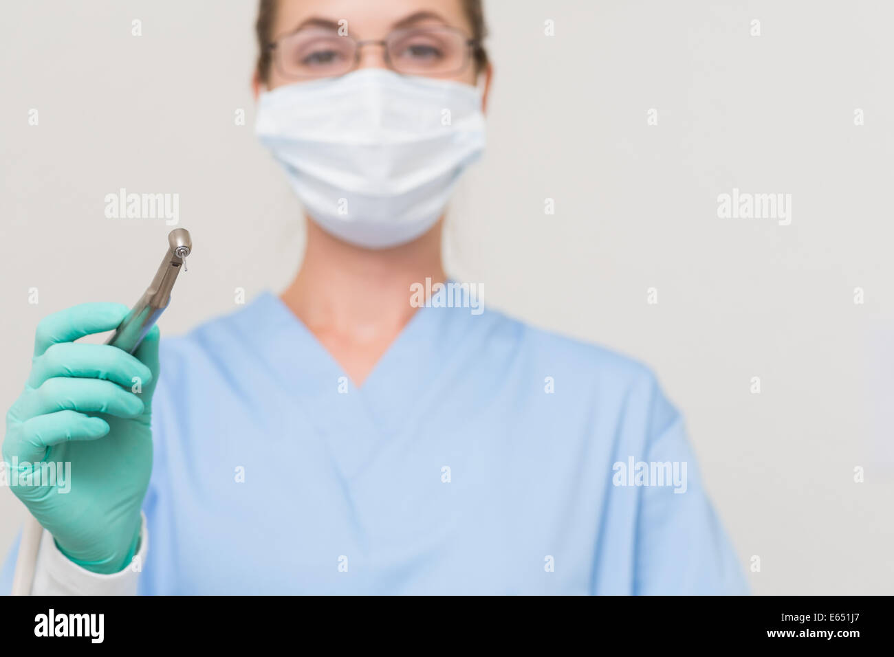 Dentiste en bleu frotte holding drill looking at camera Banque D'Images