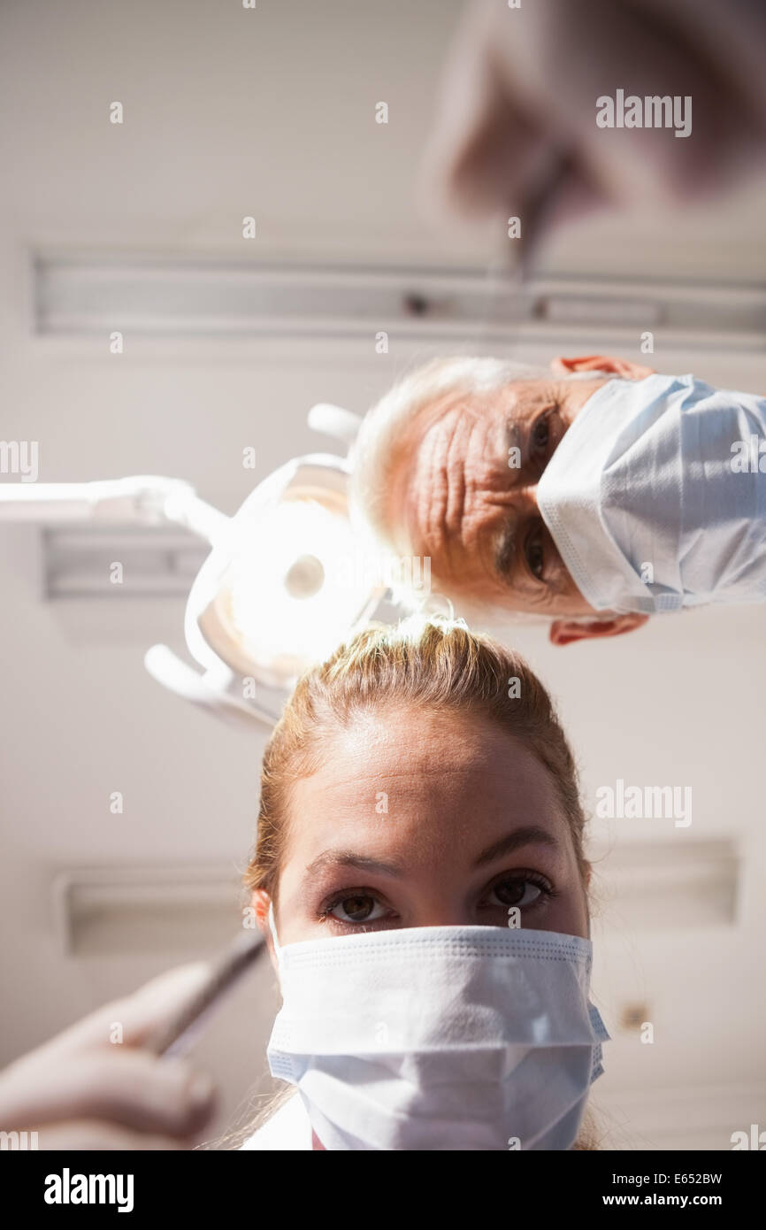 Dentiste et l'assistant se penche au patient avec des outils Banque D'Images