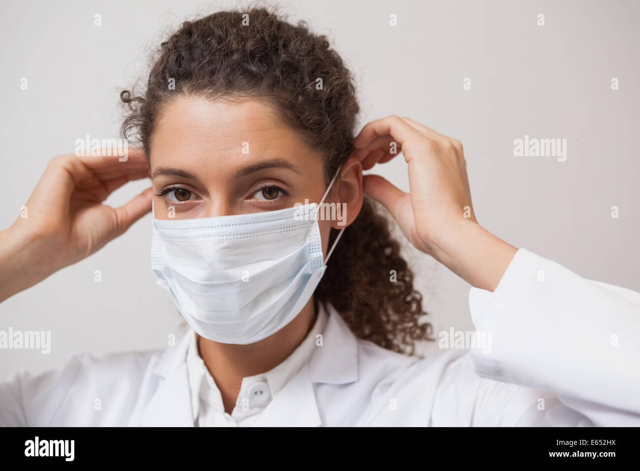 Dentiste de mettre un masque chirurgical looking at camera Banque D'Images