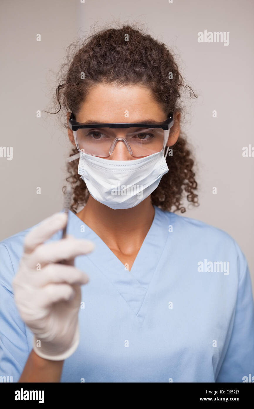 Dentiste en masque chirurgical et l'outil de maintien de gommages Banque D'Images