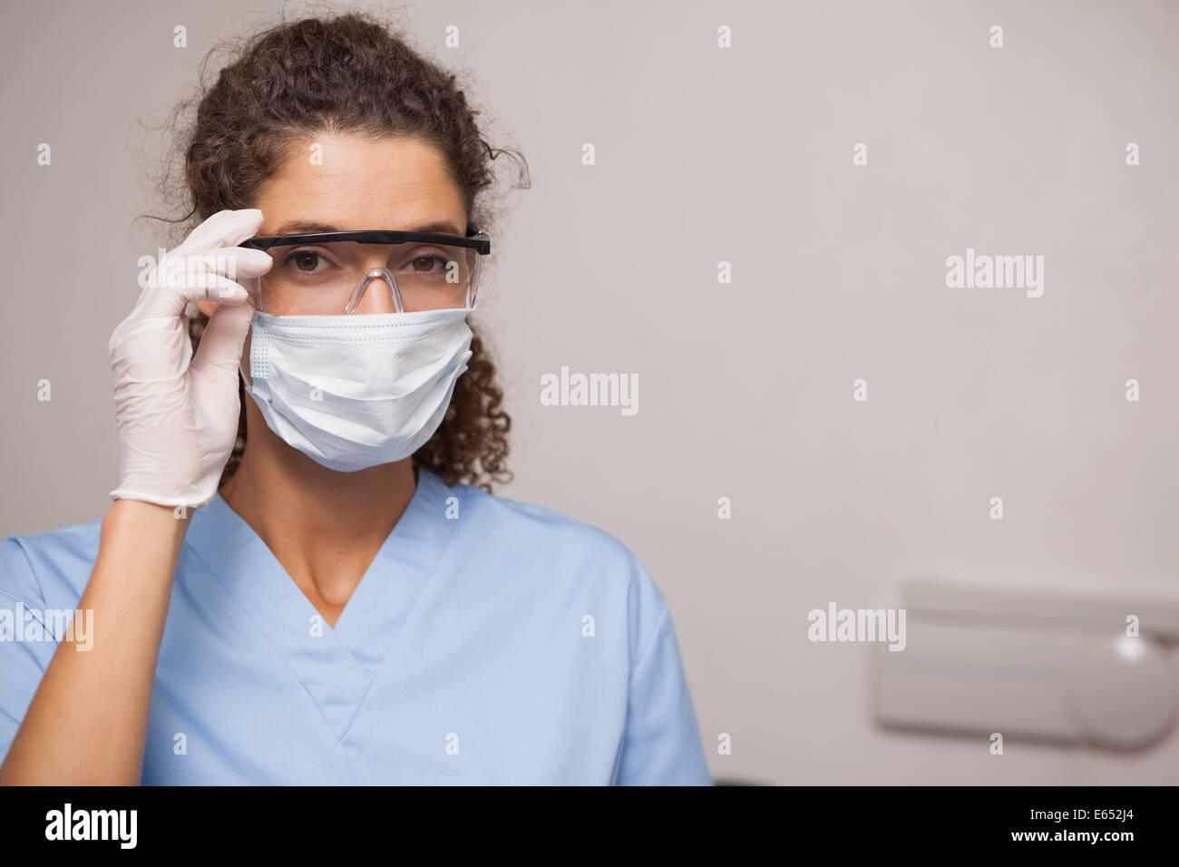 Dentiste dans un masque chirurgical et des lunettes de protection Banque D'Images