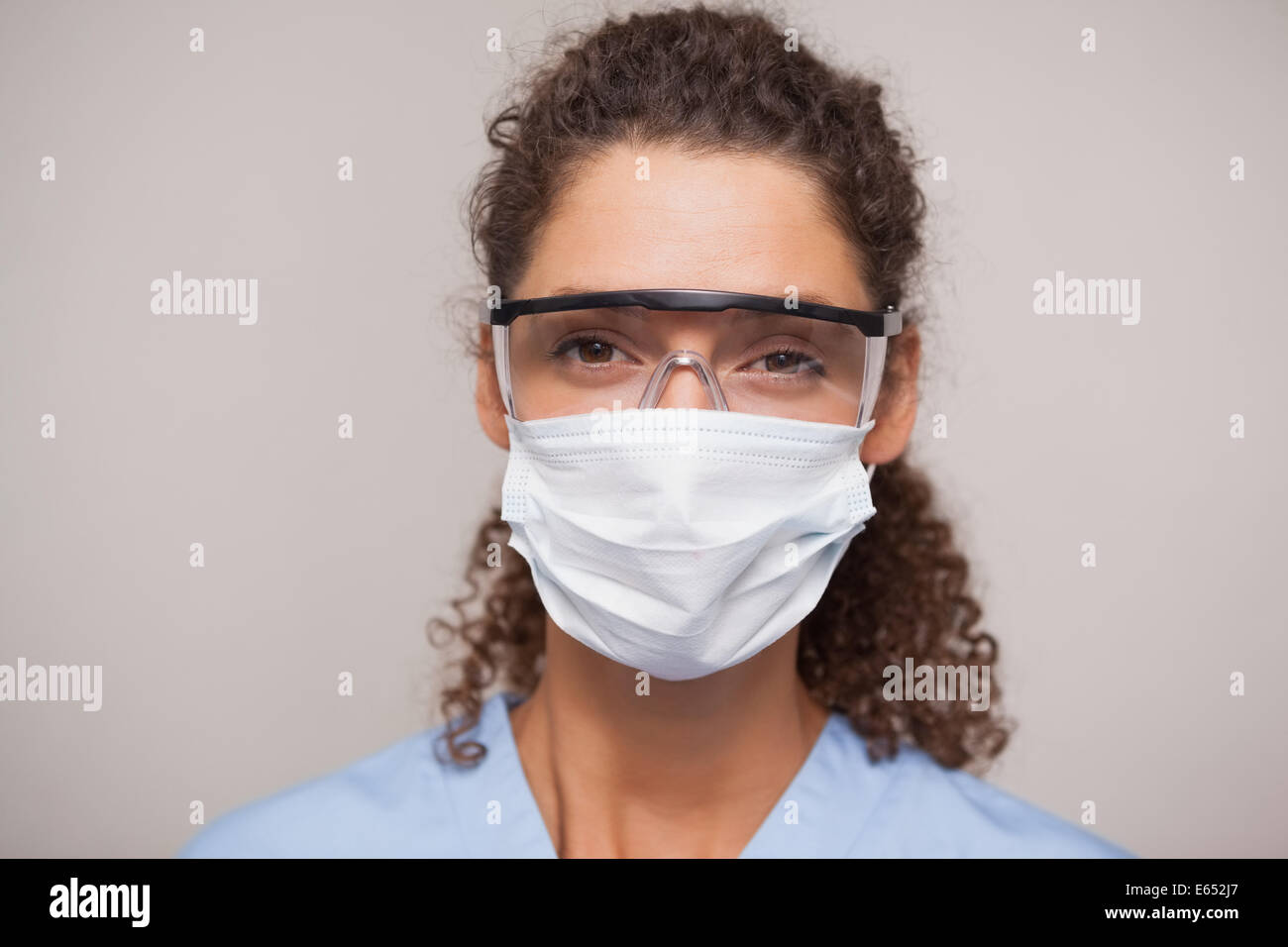 Dentiste dans un masque chirurgical et des lunettes looking at camera Banque D'Images