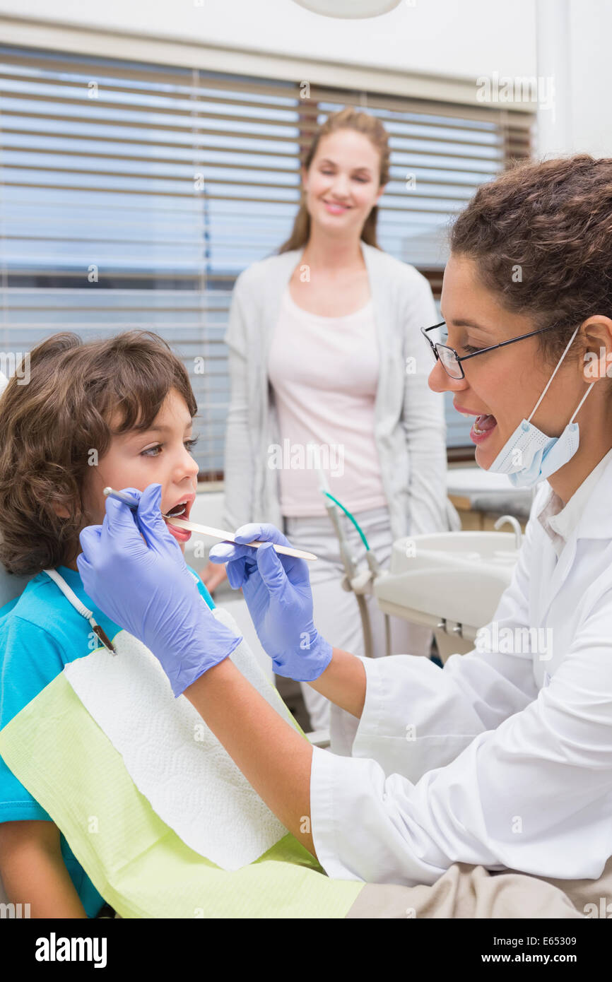 L'examen d'un dentiste pédiatrique petits garçons dents avec sa mère regarder Banque D'Images