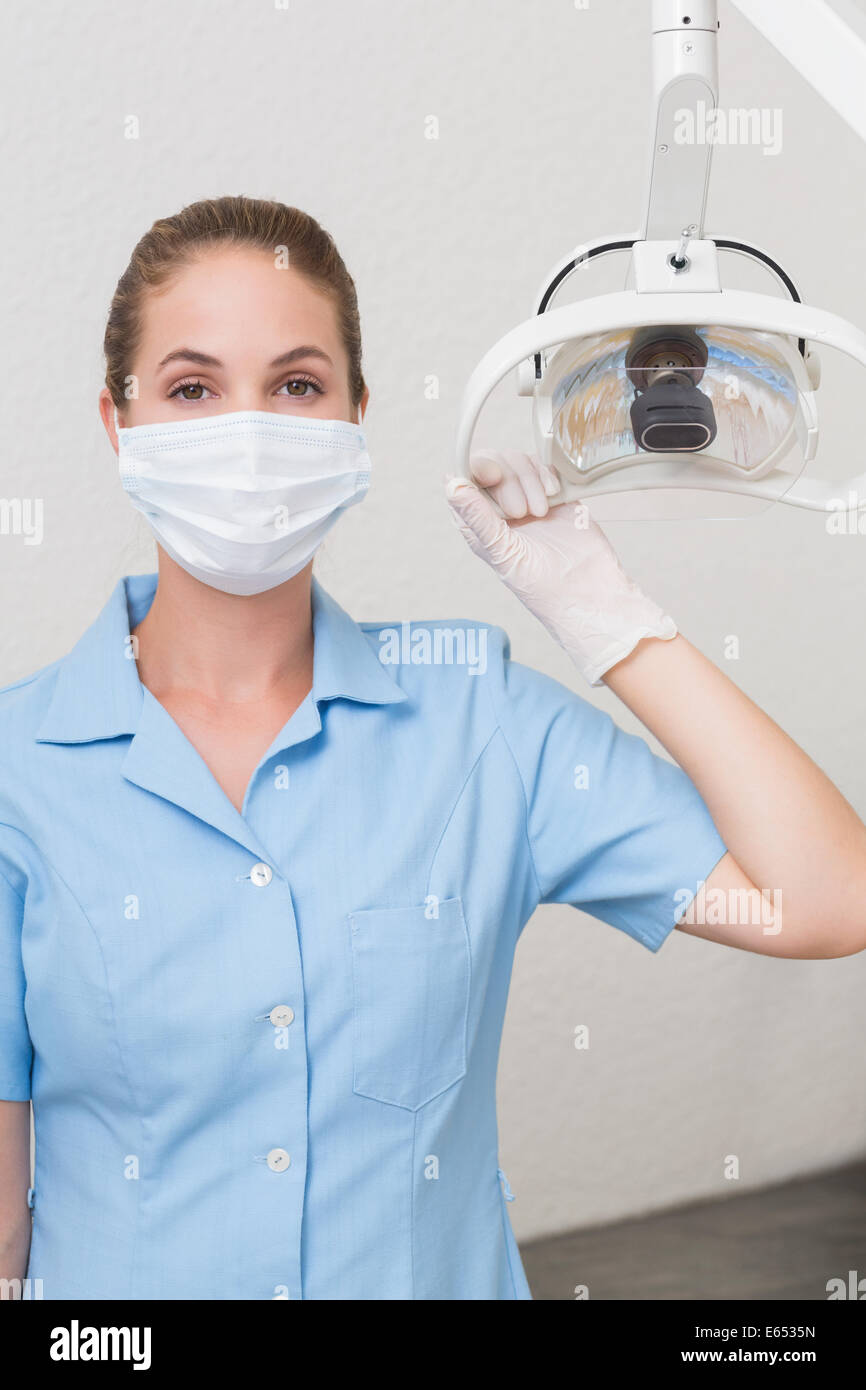 Assistant dentaire dans mask holding light Banque D'Images
