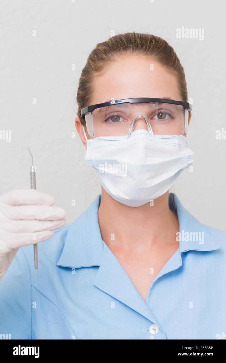 Assistant dentaire en mask holding dental explorer Banque D'Images