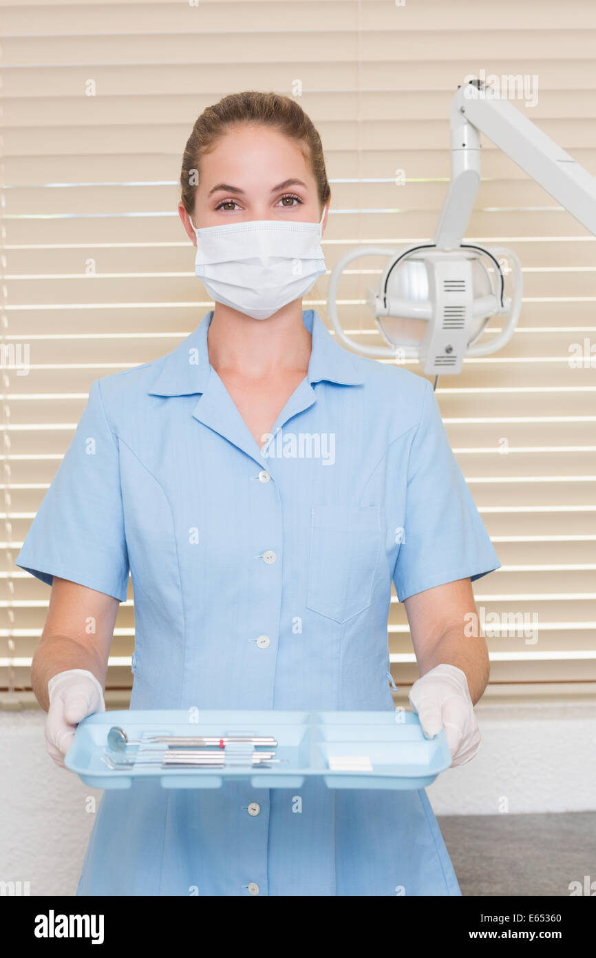 Assistant dentaire dans mask holding tray of tools Banque D'Images