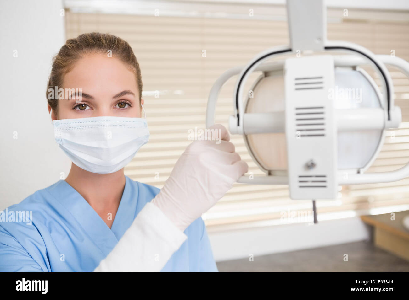 Dentiste en masque chirurgical lumière de réglage Banque D'Images