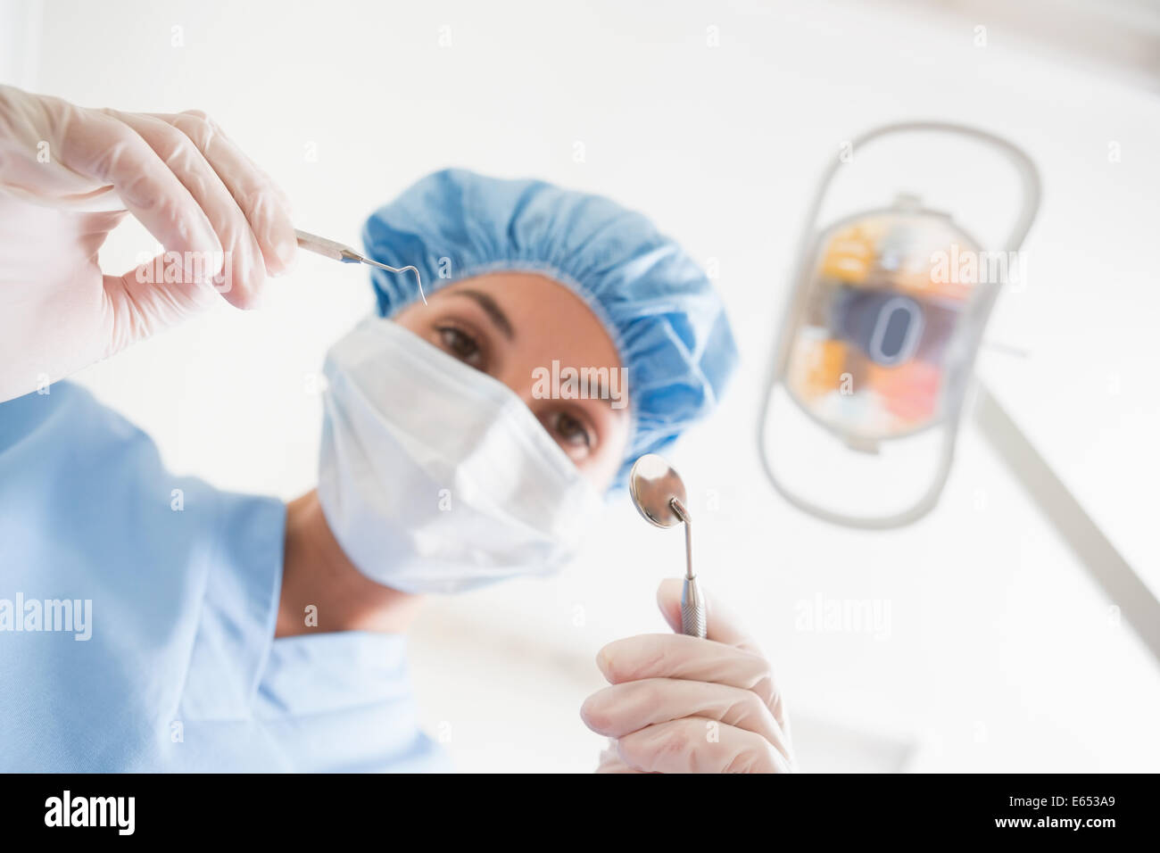 Dentiste en masque chirurgical et la tenue d'outils de dentiste sur patient Banque D'Images
