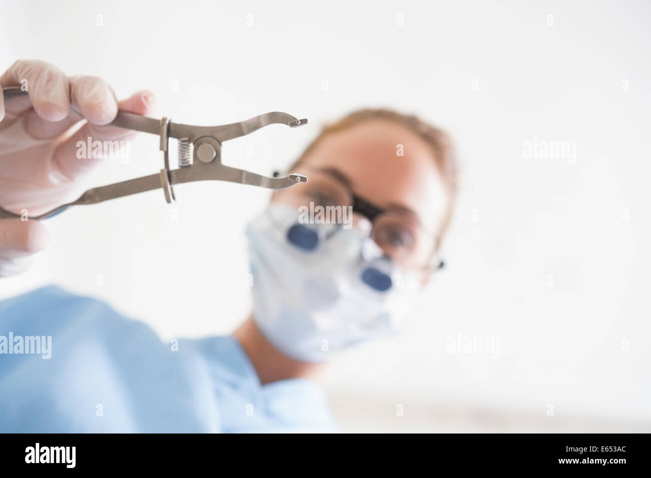 Dentiste en masque chirurgical et dentaire du patient sur une pince loupes holding Banque D'Images