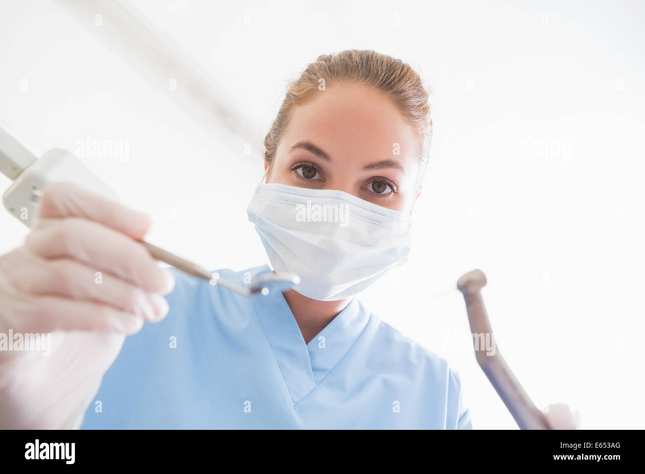 Dentiste en masque chirurgical sur les outils de maintien patient Banque D'Images
