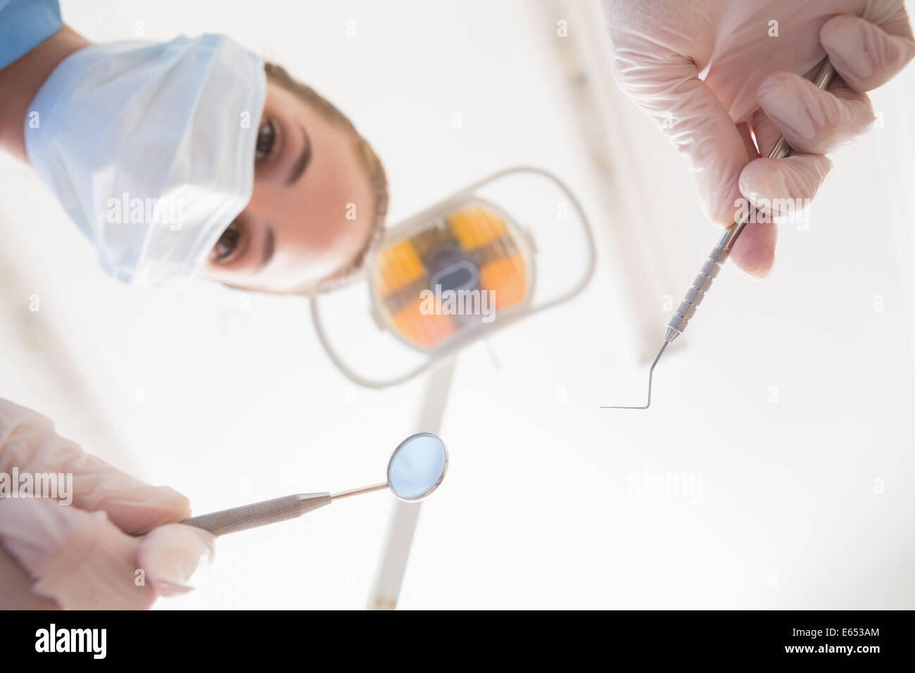 Dentiste en masque chirurgical dentaire patient plus outils holding Banque D'Images