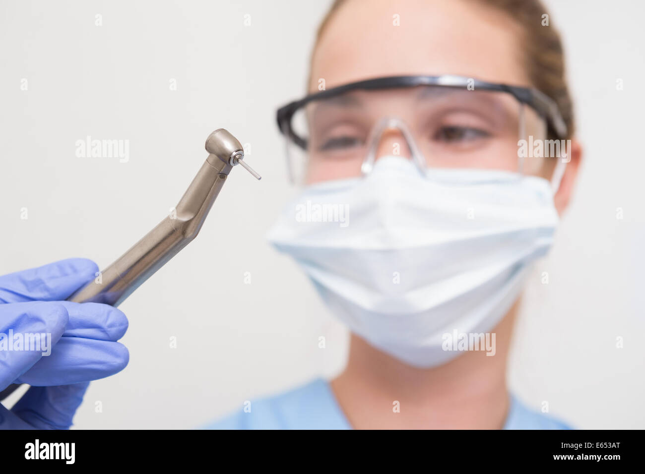 Dentiste dans un masque chirurgical et des lunettes holding drill Banque D'Images