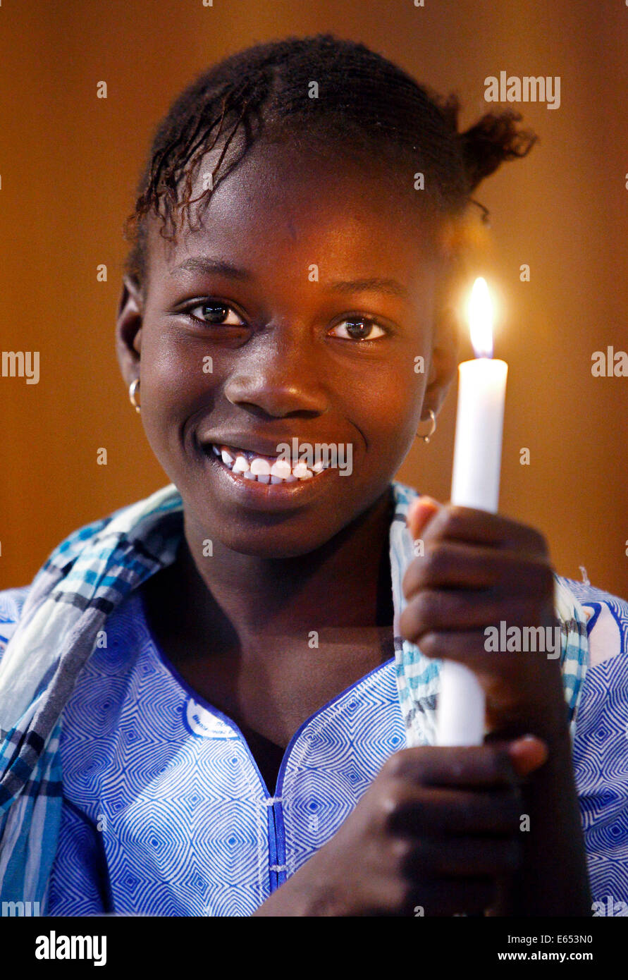 Fille (11 ans) maintenant la bougie dans une église catholique à Kaolack, Sénégal, Afrique Banque D'Images