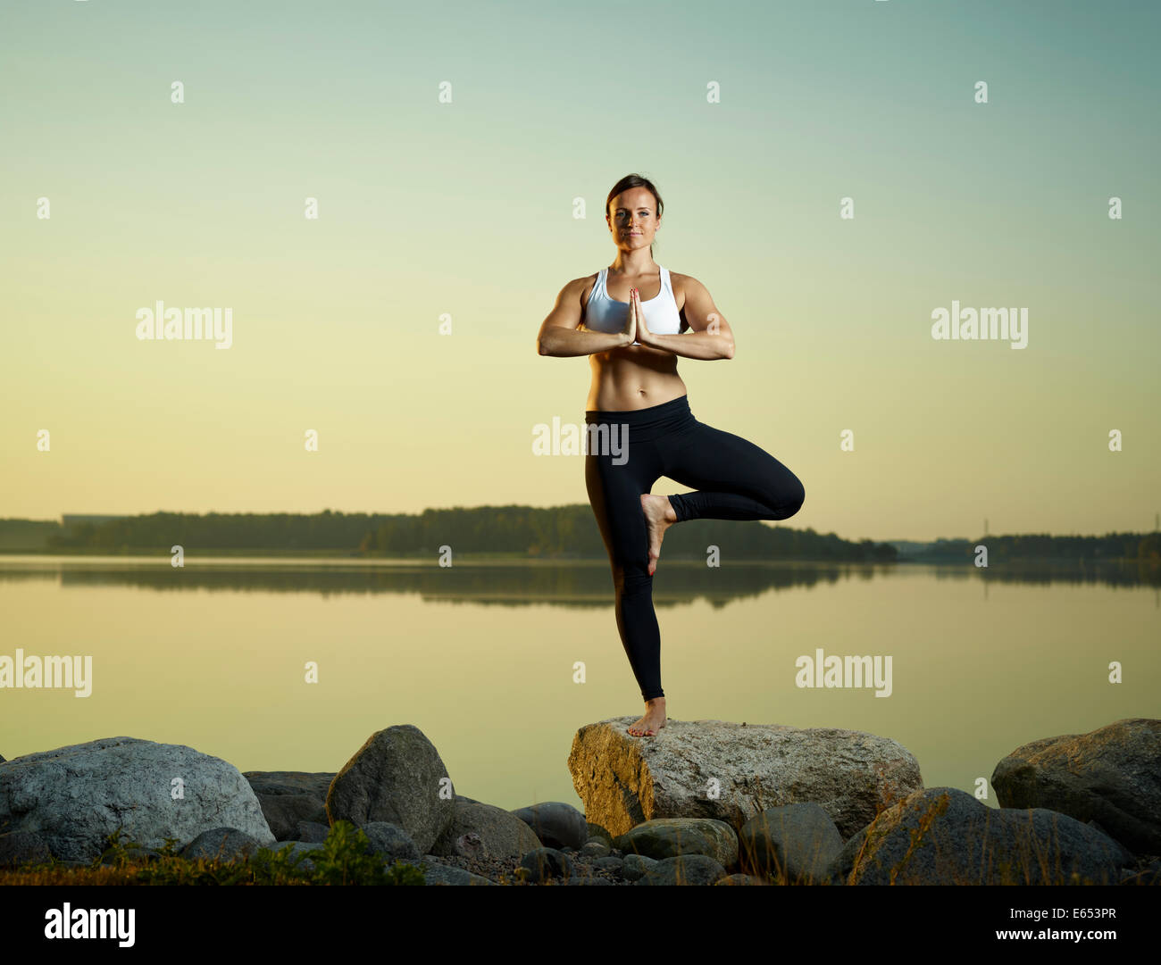 La belle jeune femme yoga exercice tôt à matin, mer calme sur l'arrière-plan Banque D'Images