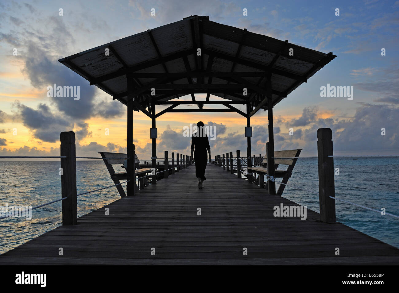 Femme marche sur la jetée en bois au lever du soleil, l'île de Bornéo, Sabah, Malaisie de l'État, en Asie du sud-est Banque D'Images