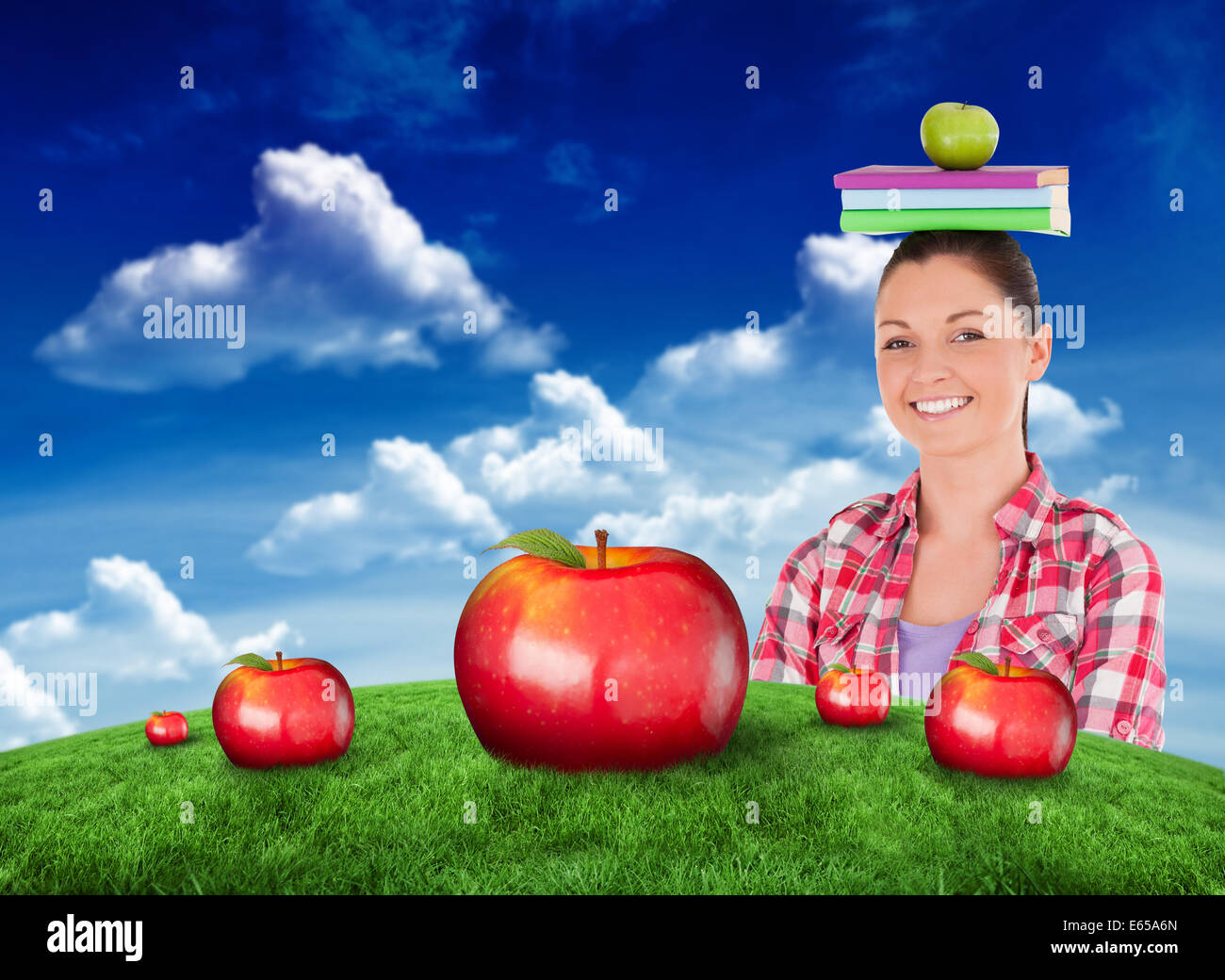 Image composite de pretty student tenant une pomme et des livres sur la tête. Banque D'Images