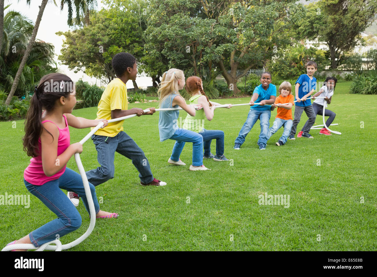 Cute pupils jouer remorqueur de la guerre sur l'herbe à l'extérieur Banque D'Images