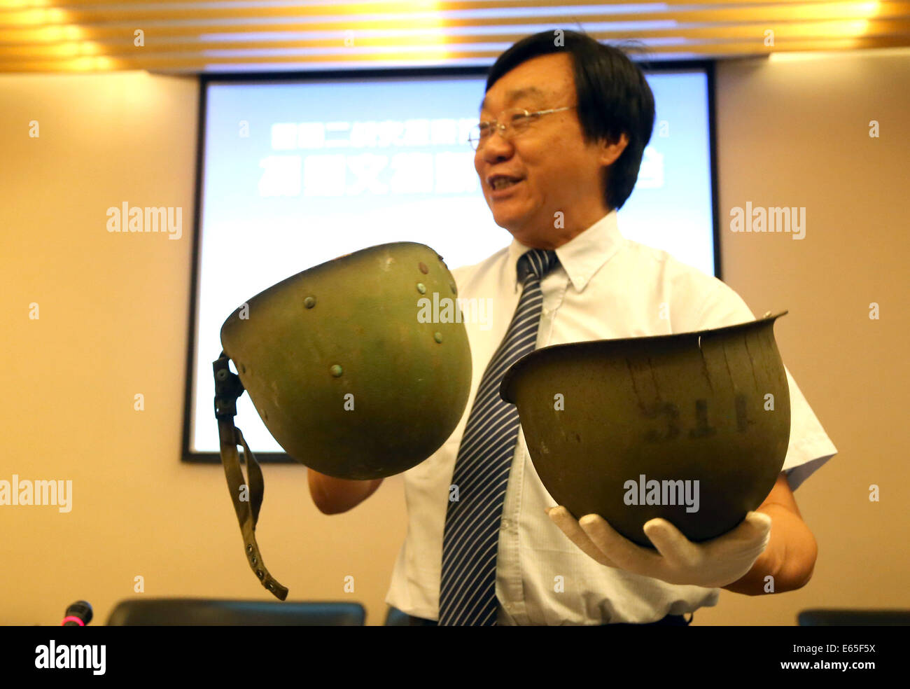 Nanjing, Chine. 15e Août, 2014. Zhu Chengshan, conservateur de la salle du souvenir des victimes à Nanjing massacre par les envahisseurs japonais, présente une double-couche casque d'acier utilisé par l'armée américaine dans la deuxième guerre mondiale, au cours d'une conférence de presse dans le hall, à Nanjing, capitale de la province de Jiangsu, Chine orientale, le 15 août 2014. Les casques, parmi les 34 pièces de guerre relique, sont donnés à la salle du Souvenir par l'association sur l'histoire de la Seconde Guerre mondiale à Kunming, capitale de la province chinoise du Yunnan au sud-ouest vendredi. Source : Xinhua/Alamy Live News Banque D'Images