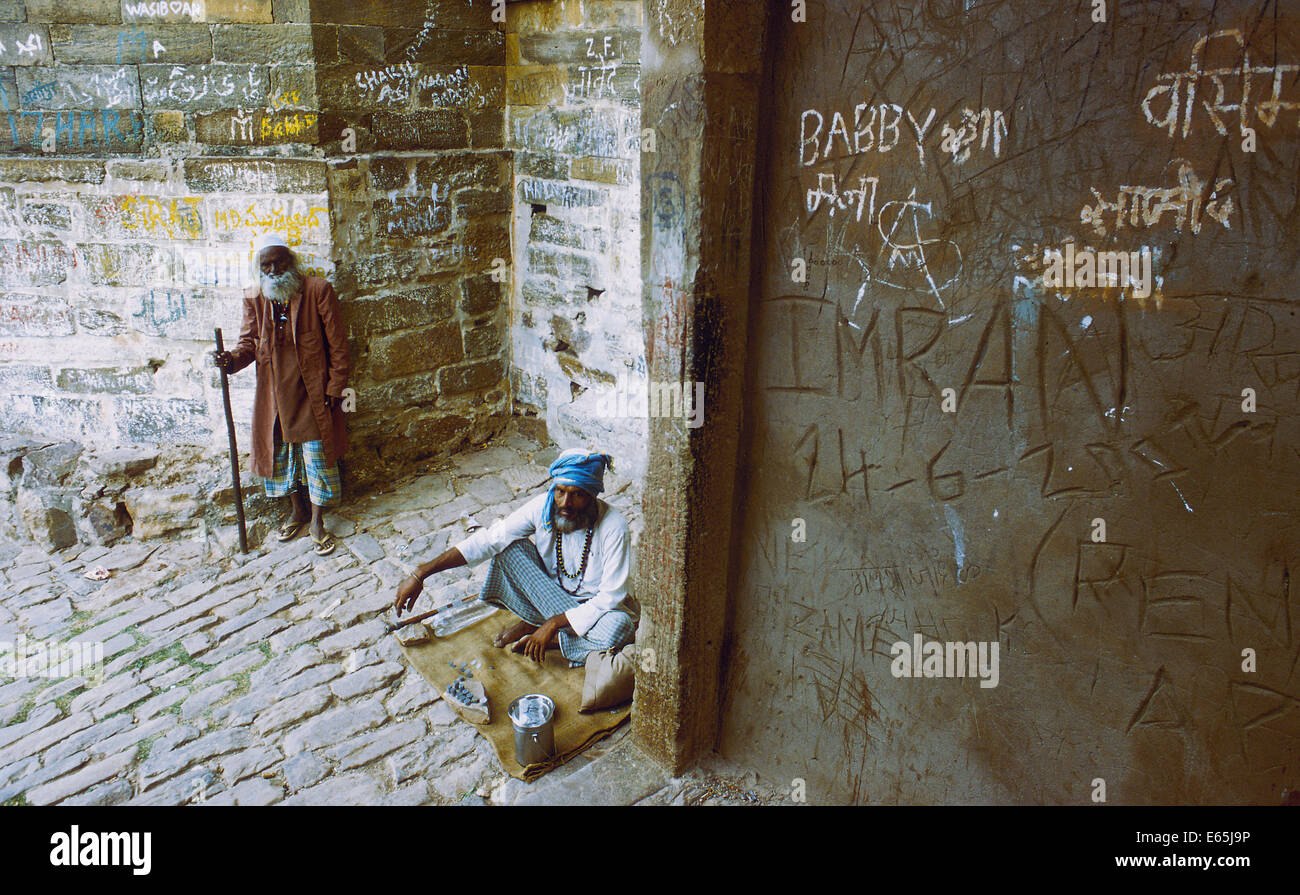 Deux fakirs sont la mendicité. Sur la droite, un mur avec de nombreux graffitis (Inde) Banque D'Images