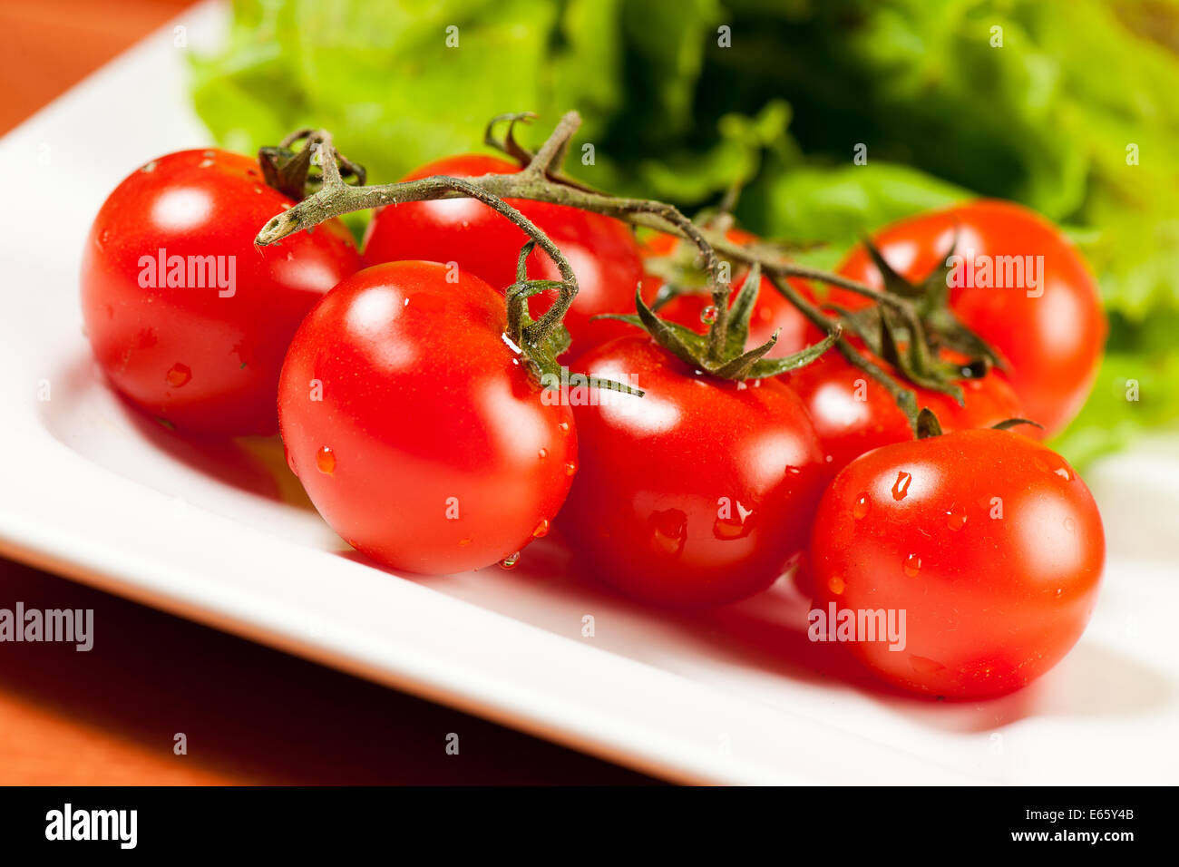 Salade de tomates sur une plaque sur une table en bois Banque D'Images