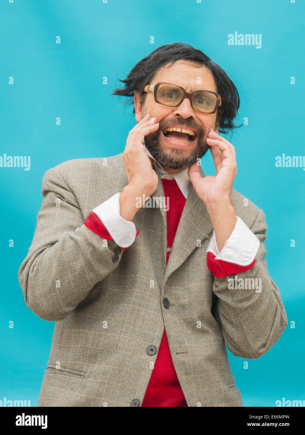 Un homme en désordre, portant des lunettes, exprimant l'horreur, sur fond bleu clair Banque D'Images